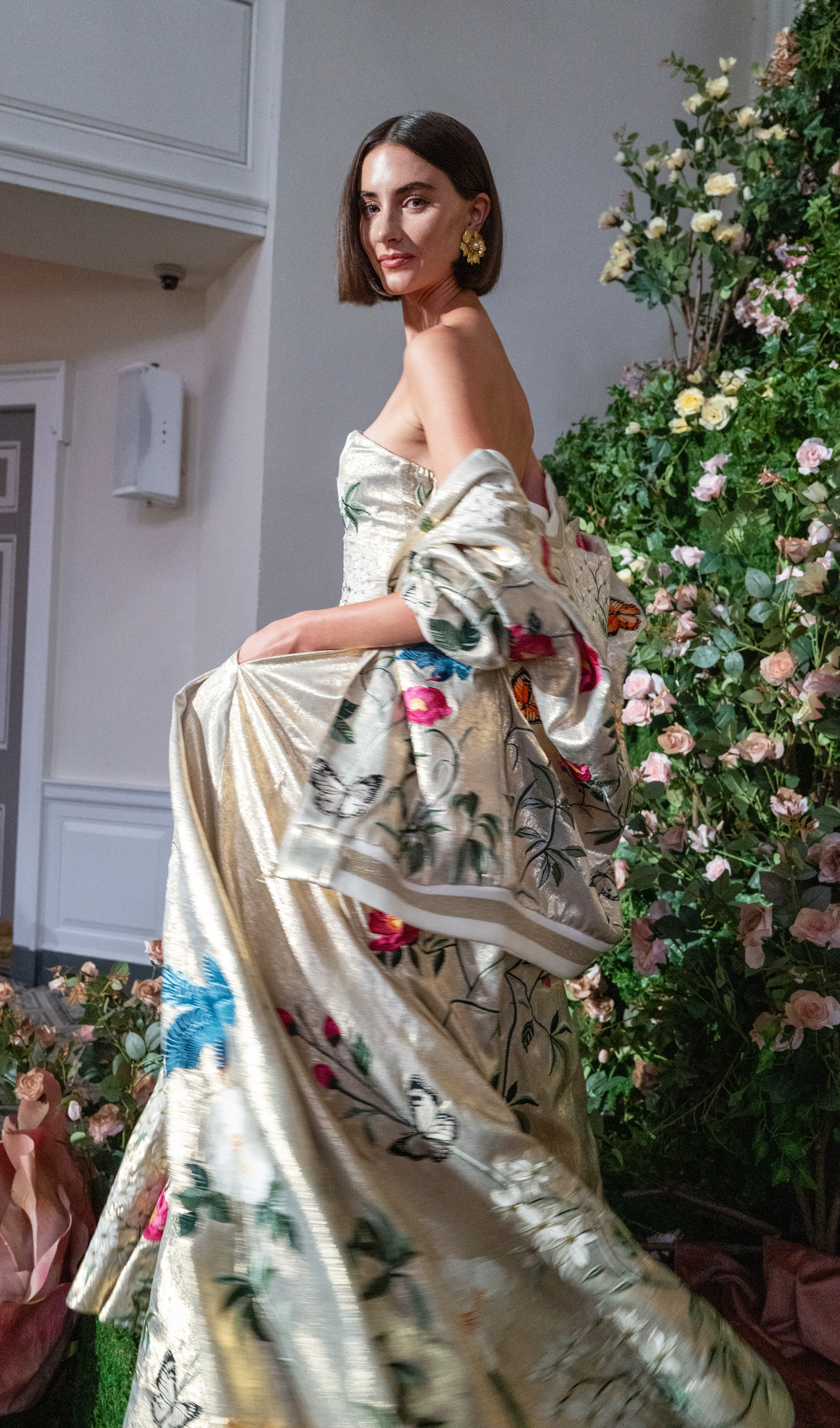A model in a metallic gold gown embroidered with butterflies and floral vines at Alice + Olivia's Wonderland presentation.