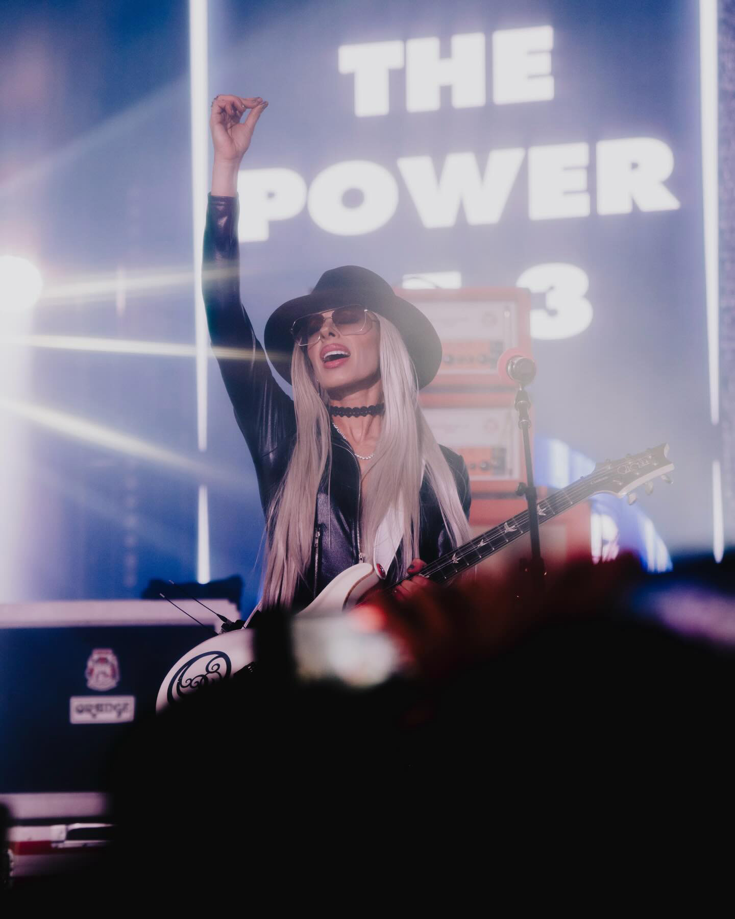 Orianthi on stage with The Power of 3 logo behind her